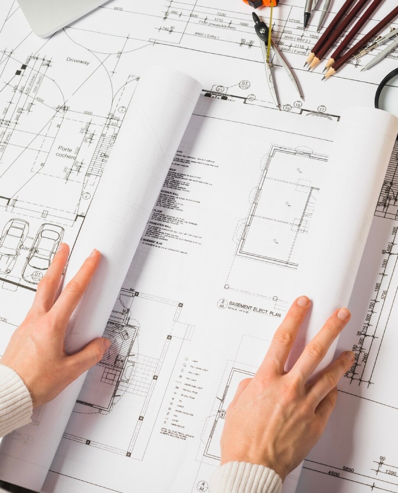 manos abriendo el plano de una casa